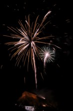 Fireworks light up the night sky above a building with glowing sparks, New Year's Eve, Stallbastei,