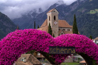 Photopoint, sign, flower heart, heart made of flowers, behind it the new parish church Maria