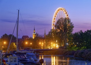 The Ferris wheel illuminated in the evening on the Motlawa, Motlawa, in the harbour district of