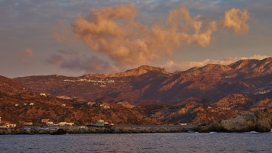 Atmospheric coastal landscape at sunrise, with dramatic clouds and mountain backdrop, Pigadia, town