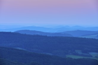 Undulating hills and mountains in blue and pink evening twilight, creating a calm and peaceful