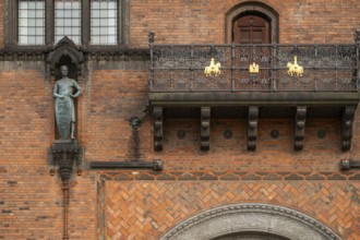 Brick façade with knight sculpture and balcony, town hall in the National Romantic style by Martin