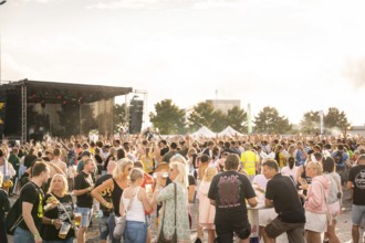 Festival visitors in front of a concert stage at sunset, lively atmosphere, Malleparty Böblingen,