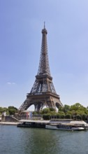 View of the Eiffel Tower on the banks of a river under a clear blue sky, Paris