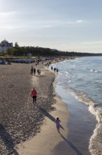 People enjoy a walk on the sandy beach along the calm seashore, Rügen, Binz