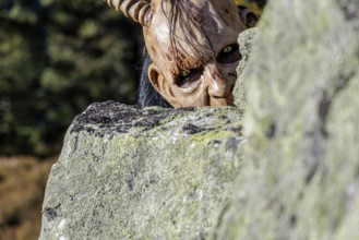 Devilish mask with horns looks out from behind a rock, Neukirchen am Großvenediger, Salzburg,