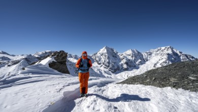 Ski tourer on foot at the summit of the Madritschspitze, mountain panorama with snow-covered