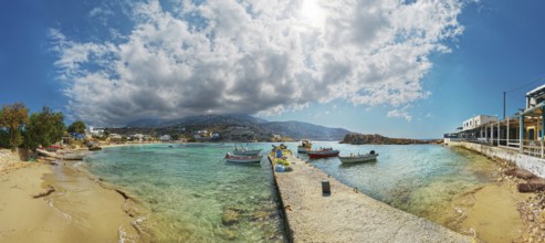 Harbour bay of the small fishing village of Arkasa with sandy beach and boats under a dramatic sky,