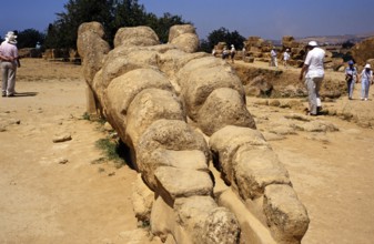 Tourists visiting the Greek ruins of the giant statue of Atlas or Telamon, Temple of Zeus, Akragas,