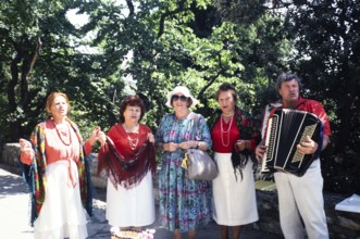 Accordion folk music group in front of Yalta, Crimea, Russia, 1997 Woman posing with the musicians,