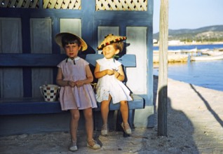 Zwei hübsche kleine Mädchen, die auf einer Barke am Meer sitzen, Insel Ibiza, Balearen, Spanien,