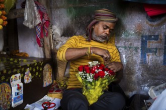 Vendor makes rose bouquet to sell in a street flower shop, on the occasion of Valentines day on