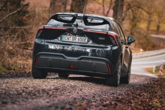 Black car driving on a rural road in autumn, e-car sharing, Deer Mobility, MG4, Calw, Germany,