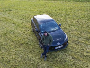 Man leaning against a black car on a green field, e-car sharing, Deer Mobility, MG4, Calw, Germany,