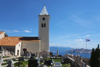 Church tower and gravestones with a view of the sea and mountains, Croatian flag, peaceful