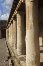 Old large building covered with terracotta clay roof tiles and supported by stone columns at the