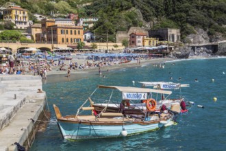 Moored turquoise, red tour boats fitted with canvas bimini tops in bay, Monterosso village, Cinque