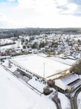 Residential area and sports field under a blanket of snow surrounded by wintry trees and buildings,