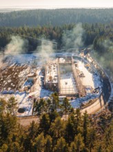 Snow-covered construction site in the forest with cranes and areas surrounding trees, new fire