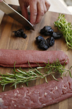 Swabian cuisine, preparation of lamb with prunes, raw lamb, rosemary, herbs, sliced garlic, lemon