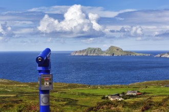 Viewpoint with blue telescope, coin-operated telescope on the coast, rocky islands on the horizon,