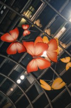 Artistic representation of large red and orange butterflies under an illuminated railing, Calwer