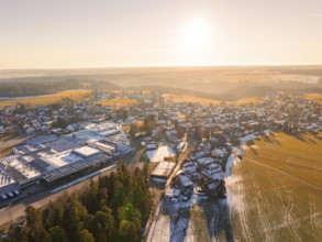 Village in winter landscape with fields and an industrial area, illuminated by the sunset,