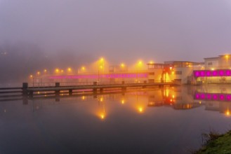 The illuminated weir of Lake Baldeney in Essen, in heavy fog, foggy weather in winter, North