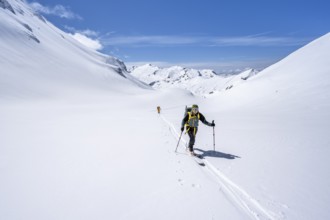 Two ski tourers in a mountain landscape with snow, behind summit Mittaghorn and Wildhorn, ascent to