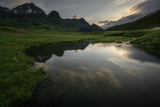 Summit in the morning light with dramatic clouds and stream in the foreground, Lech,