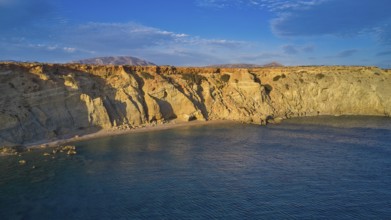 Rocky cliffs at sunset with calm water and natural beauty, drone shot, evening light, Paralia Agios