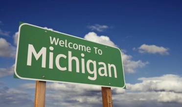 Welcome to michigan green road sign over blue sky with some clouds