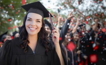 Young female graduate celebrating her graduation with her fellow classmates outdoors