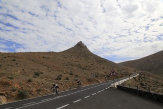 Cyclists on interior road through mountains, Fuerteventura, Canary Islands, Spain, Europe