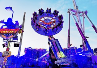 People on the illuminated carousel Mr Gravity in the evening, Cranger Kirmes, Herne, Ruhr area,