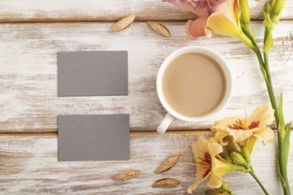 Gray paper business card mockup with orange day-lily flower and cup of coffee on white wooden