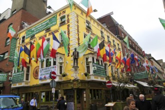 Flags outside colourful yellow Oliver St John Gogarty pub in Temple Bar area, Dublin city centre,