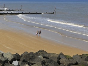 Family walking sandy beach at Sheringham, Norfolk, England, UK