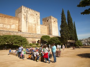 Children on a school trip sitting outside the fortified castle walls of the historic Alcazaba, of