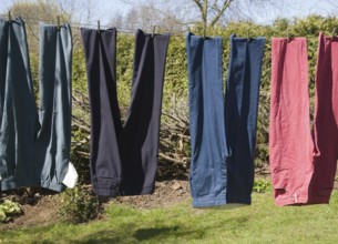 Trousers of different colours hanging from washing line, UK