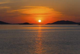 Red sky and sunset over calm water with islands, view from island Murter, Dalmatia, Croatia, Europe