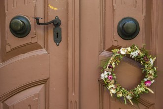 Detail of an antiquated front door with floral wreath in a building on the Krämerbrücke in the