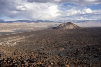 Vast landscape with a volcano and distant mountains under clouds, Argentina, volcanoes, lava field,