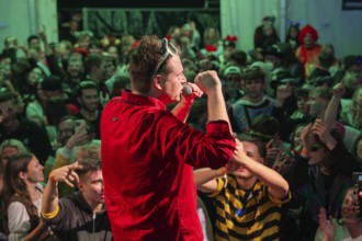 Schlager king Tobee in red shirt sings on stage in front of a rousing audience, carnival,