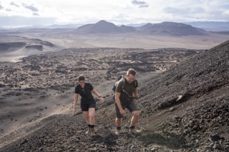 Two hikers climb up a rocky volcanic slope, Argentina, Volcanoes, Lava field, Antofagasta, South