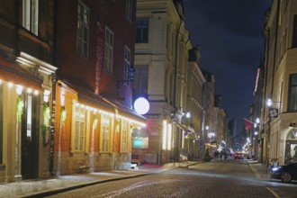 Night shot of a cosy street with old buildings and warm lantern light in a city, winter, Gamla