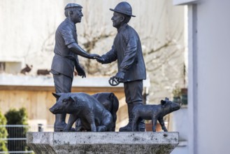 Butcher and farmer haggle over the price of a pig. Statue group in memory of the Ulm mule market.