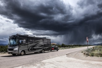 Motorhome with boat trailer driving through wild thunderstorm and rain clouds over Highway 50,