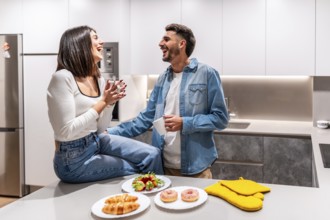 Young couple laughing and having breakfast in a modern kitchen, enjoying a moment of happiness