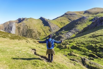 Hiker with open arms enjoying the breathtaking panorama of mount txindoki in gipuzkoa, basque